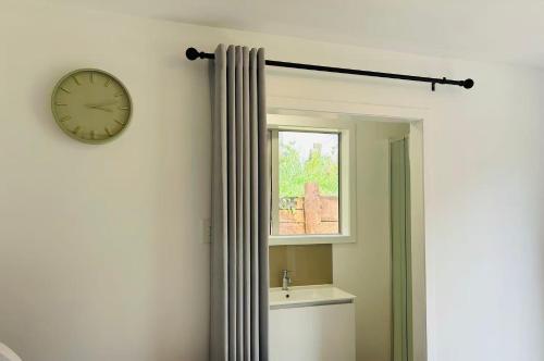 a bathroom with a clock on the wall next to a window at Mystery Creek Motel in Hamilton