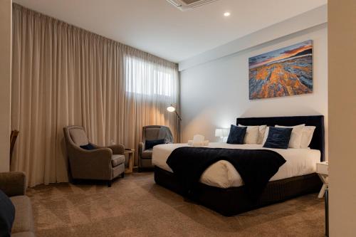 a hotel room with a bed and a chair at Bay Of Fires Apartments - Town Centre in St Helens
