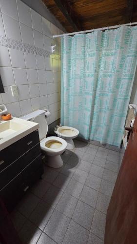 a bathroom with two toilets and a blue shower curtain at Casa Refugio in Paso de la Patria