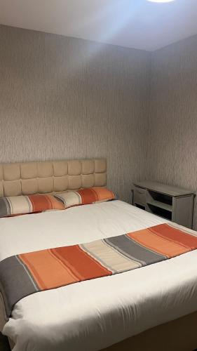 a bedroom with a large bed with an orange and brown blanket at Workers Contractor friendly home long and short stays in Grimsby