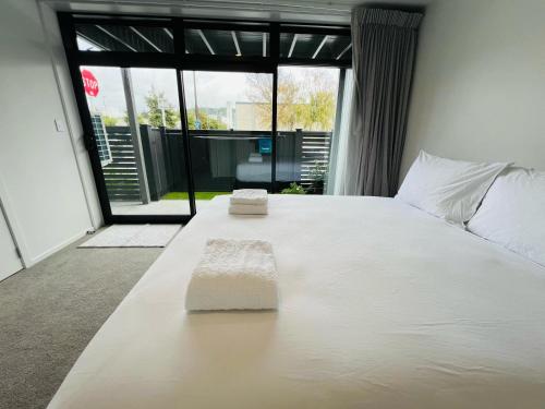 a white bed in a room with a large window at Lower Hutt Central Brand New 3 bedroom 2 Bath Spacious House Balcony Private garage in Lower Hutt
