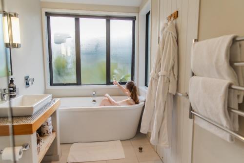 a young girl sitting in a bath tub in a bathroom at Manakau Lodge in Kaikoura