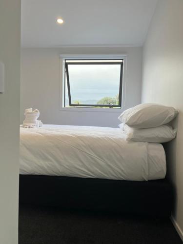 a bed with pillows and a window in a room at Central Modern 3-Bedroom,3- Bathroom House with Patio and Carpark- Lower Hutt City Centre in Lower Hutt