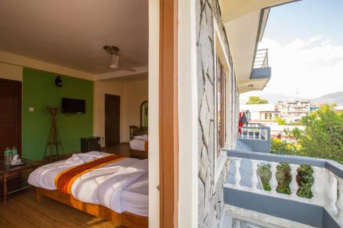 a bedroom with a bed and a balcony at Hotel Pokhara View in Pokhara