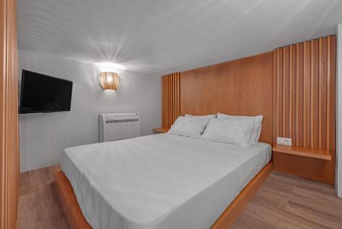 a bedroom with a large white bed with a flat screen tv at Rhodes center Santa Mari in Rhodes Town