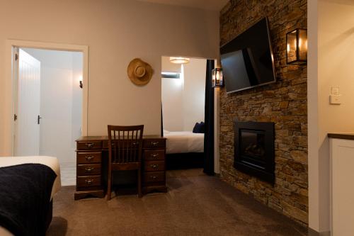 a bedroom with a fireplace and a tv on a brick wall at Bay Of Fires Apartments - Town Centre in St Helens