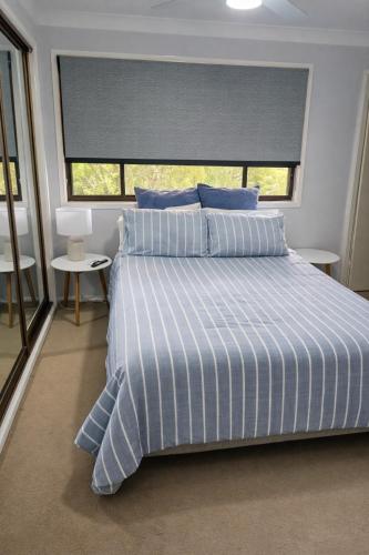 a bed with a blue and white striped comforter in a bedroom at Allawah Hideaway Tamworth in West Tamworth