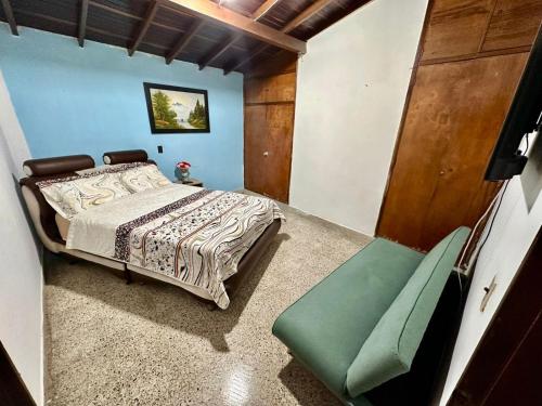 a bedroom with a bed and a green chair at Hostel Urban City Medellin in Medellín