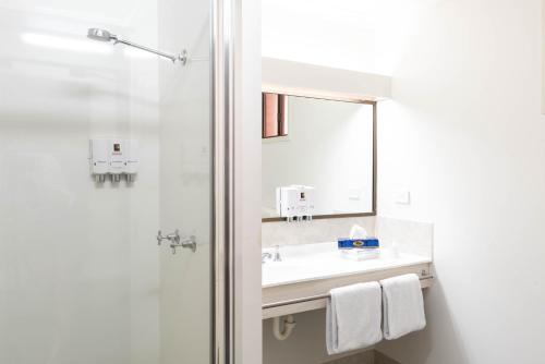 a bathroom with a shower and a sink and a mirror at Longreach Motor Inn in Longreach