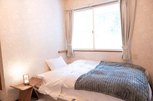 a bedroom with a bed with a window and a table at 歩絵夢の森 Pension Poem no mori in Hakuba
