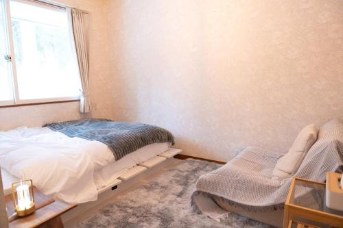 a bedroom with a bed and a window at 歩絵夢の森 Pension Poem no mori in Hakuba