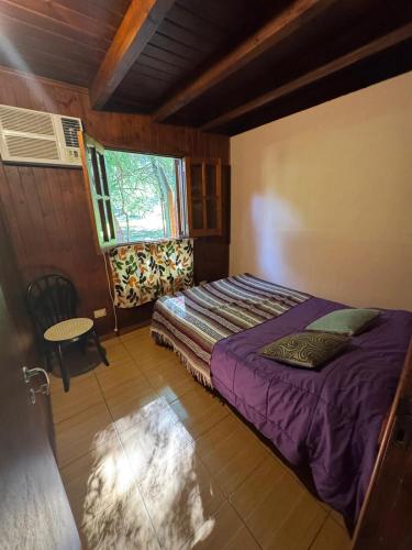 a bedroom with a bed and a table and a window at Cabaña DOS Refugio in Paso de la Patria
