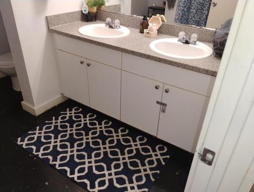 a bathroom with two sinks and a black and white rug at The Downtown Stadium Loft in Memphis
