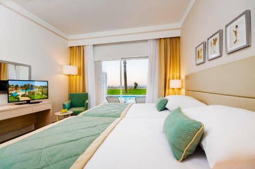 a hotel room with two beds and a television at JAZ Aquaviva in Hurghada