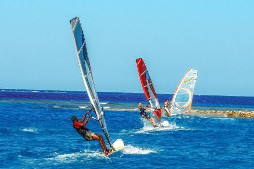 three people are windsurfing in the ocean at JAZ Aquaviva in Hurghada