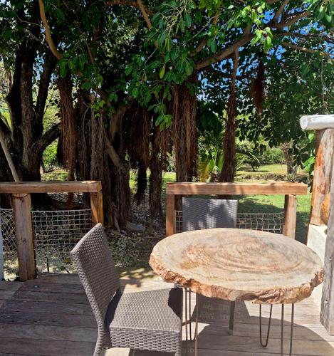 a table and chairs on a wooden deck with a tree at Villa Rose Barth Location de Chambre in Saint-Louis