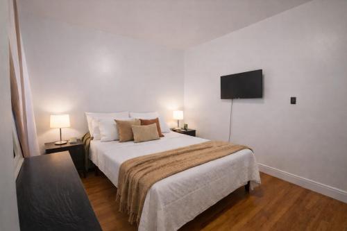 a bedroom with a large bed and a flat screen tv at Bronx City Stay Private Room Near Manhattan in Kings Bridge Heights