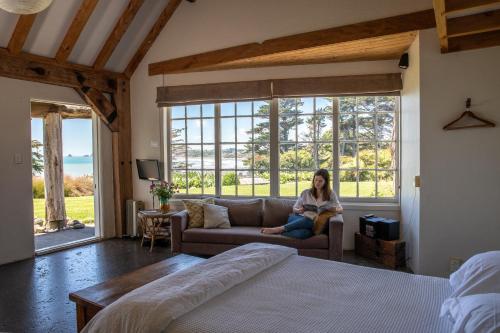 a woman sitting on a couch in a room with a window at Ahu Ahu Beach Villas in Oakura