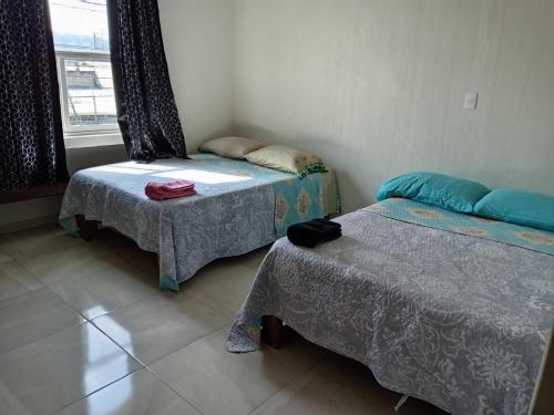a room with two beds and a table and a window at Hotel Mi Casa Mata in Morelia