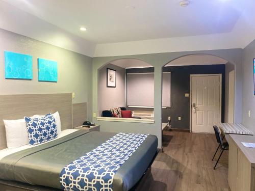 a bedroom with a large bed with a desk and a room with at Island Suites Hobby Airport in Houston