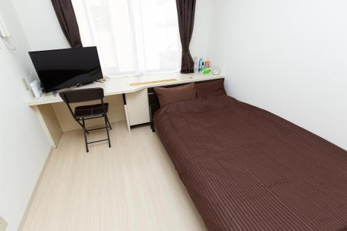 a bedroom with a bed and a desk with a computer at アセット北初富 - 長期滞在歓迎 キッチン付きで一人旅やビジネス出張におすすめ 成田空港へ直通 in Kamagaya