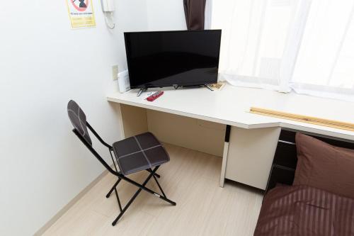 a desk with a computer monitor and a chair at アセット北初富 - 長期滞在歓迎 キッチン付きで一人旅やビジネス出張におすすめ 成田空港へ直通 in Kamagaya