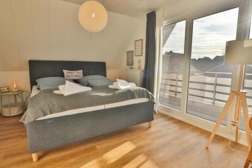 a bedroom with a large bed and a large window at Blüten & Meer - Haus Meer in Langeoog