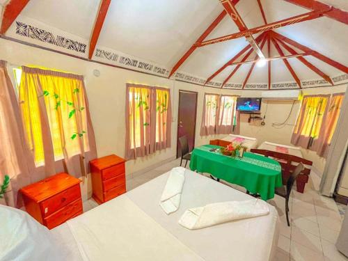 a room with a green table and a dining room at Talanoa Fales Accommodation in Apia