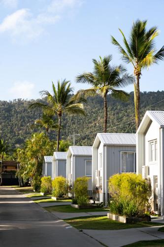 a row of houses with palm trees and a mountain at Tasman Holiday Parks - Airlie Beach in Airlie Beach