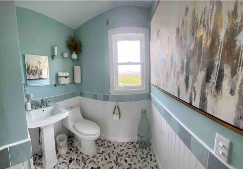 a bathroom with a toilet and a sink at Nautical Endeavors Beach House Steps from Surf in Rodanthe