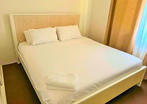 a bed with white sheets and pillows in a room at The Unit Lennox Head in Lennox Head