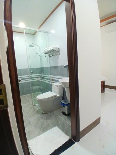 a bathroom with a toilet and a glass shower at Nhi Quỳnh La Gi Hotel in Lagi