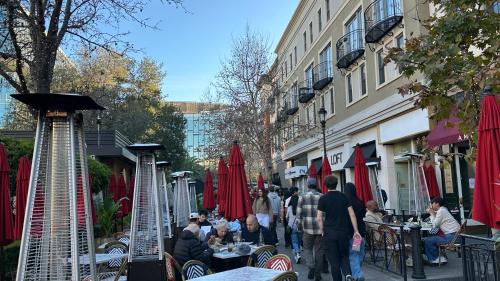 a group of people walking down a street with tables at Santana Row Garden Retreat Private Executive Residence with Koi Pond and Waterfall Walk to Santana Row Valley Fair Dining and Shopping Private Entrance in San Jose