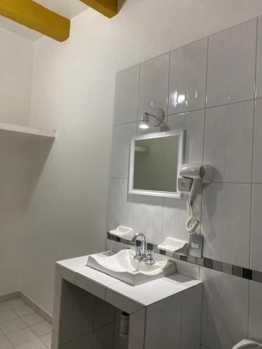 a white bathroom with a sink and a mirror at Hotel Jocari in Cholula