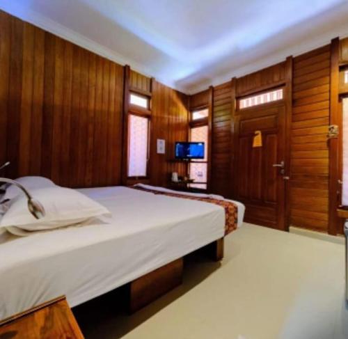 a bedroom with a large bed and a television at Baron Ndut's Cottage in Mantaak