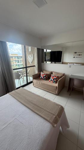 a bedroom with a bed and a couch and a table at Flat Inteiro no Makia Beach Experience in Porto De Galinhas