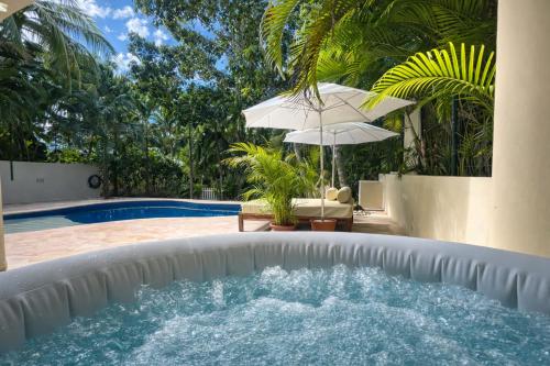 a swimming pool with an umbrella next to a swimming pool at 7BR Private Jacuzzi & Pool Villa Sleeps 16 Walk to Beach Lagoon and Golf in Puerto Aventuras