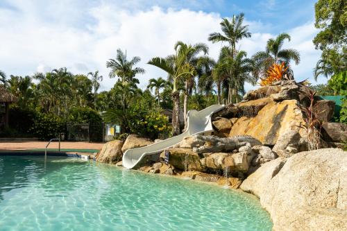 a water slide in a swimming pool with rocks at BIG4 Tasman Holiday Parks - South Mission Beach in South Mission Beach