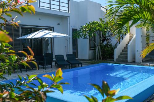 a pool in front of a house with an umbrella at Blue Ocean Resort in Ishigaki Island