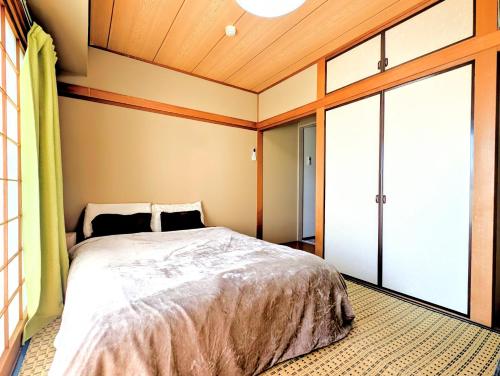a bedroom with a bed and a sliding glass door at Apt熱海 in Atami
