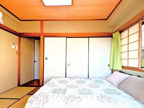 a bedroom with a bed and a window at Apt熱海 in Atami