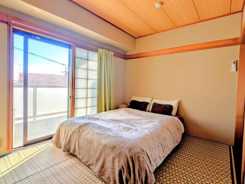 a bedroom with a bed and a large window at Apt熱海 in Atami