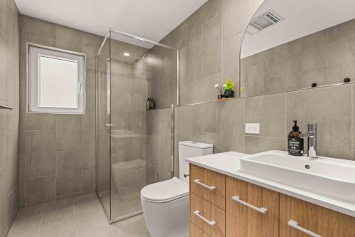 a bathroom with a toilet and a shower and a sink at Blenheim Breeze by Experience Jervis Bay in Vincentia