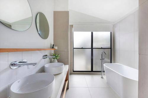 a white bathroom with two sinks and a mirror at Reflections Byron Bay - Holiday Park in Byron Bay