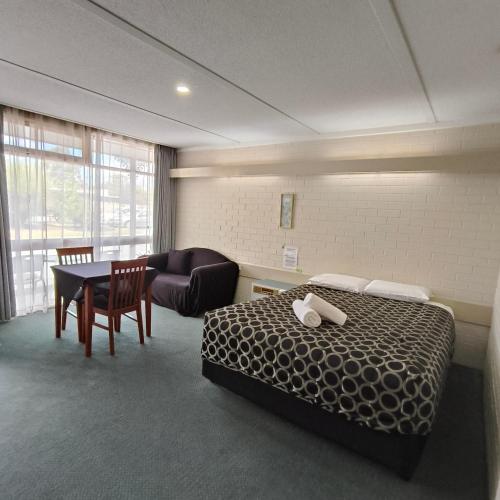a hotel room with a bed and a table and a couch at Wangaratta Motor Inn in Wangaratta