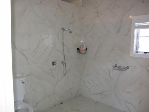 a bathroom with a shower with white marble walls at Woodhey Retreat Unit 2 in Karapiro