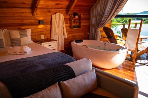 a bedroom with a bed and a bath tub at Cabana Terra - Hidro com vista, Lareira e Café da manhã in Nova Petrópolis