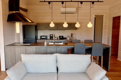 a living room with a couch and a kitchen at パインズコテージ八ヶ岳 トゥースラ in Hokuto