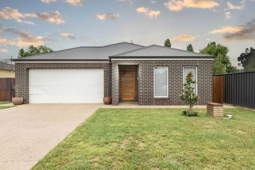 a brick house with a garage in a yard at Lavender & Olive in Myrtleford