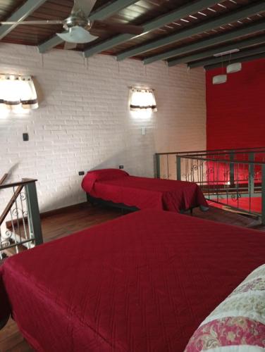 a room with two beds with red sheets in it at Morada de Duendes in Sauce Viejo